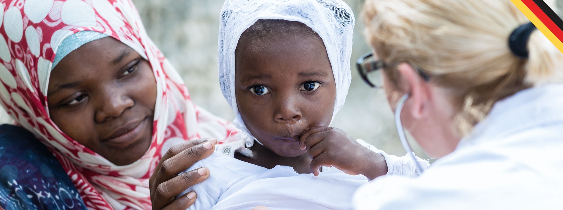 Child with mother receiving medical attention outdoors.