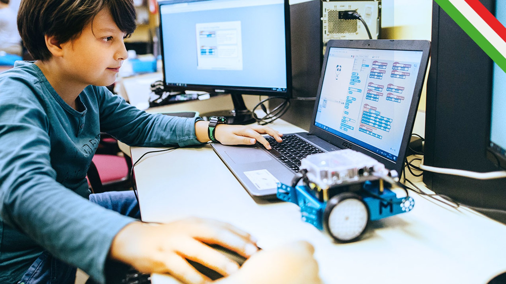 Child programming with robot and computer setup.