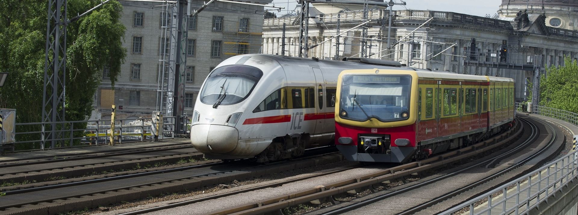 Two trains on tracks near a building.