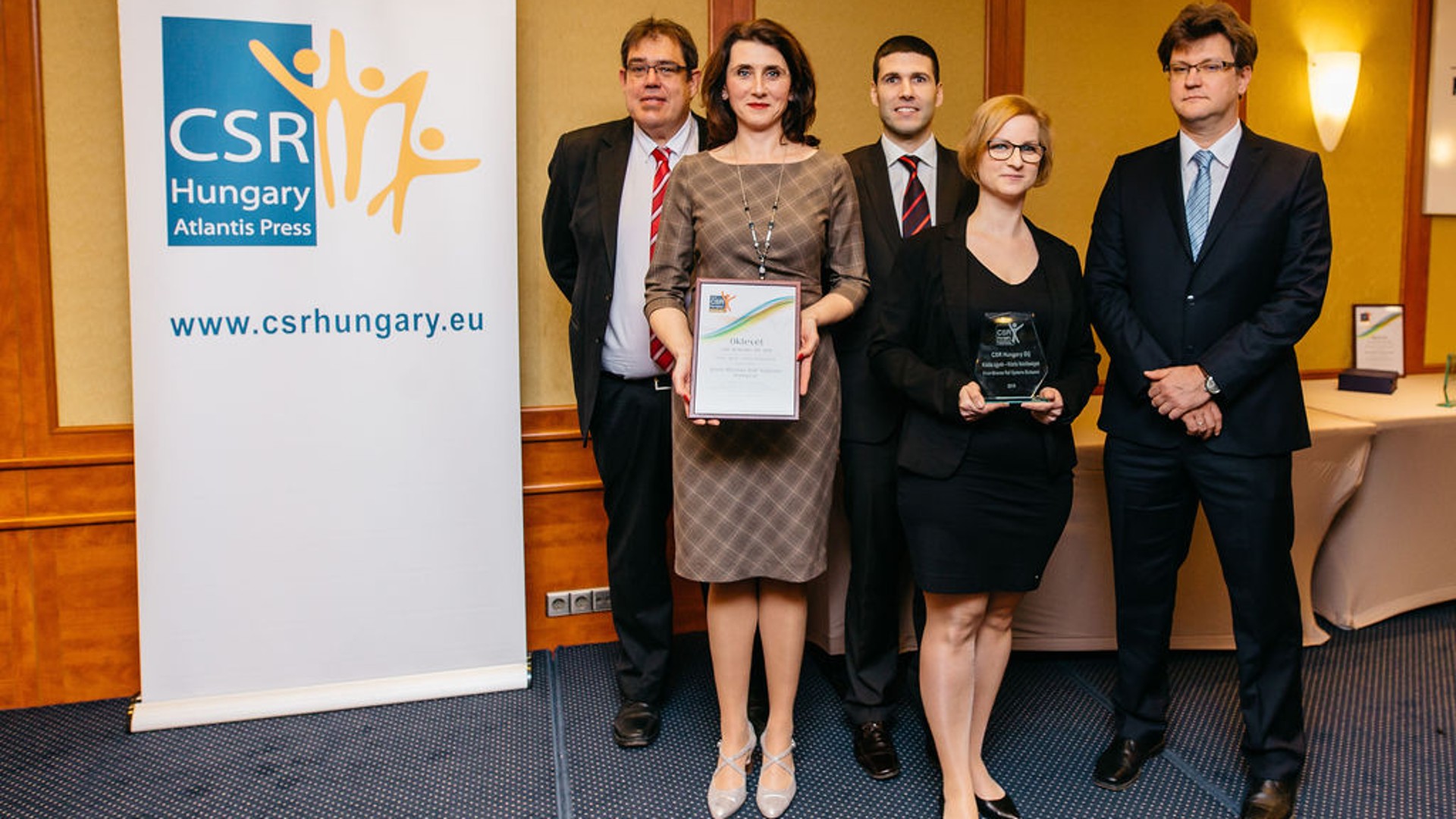 Award ceremony with five professional individuals posing.