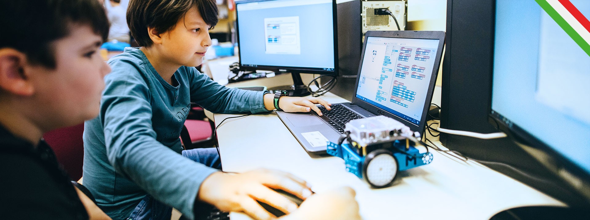 Children coding with computers and robot vehicle.