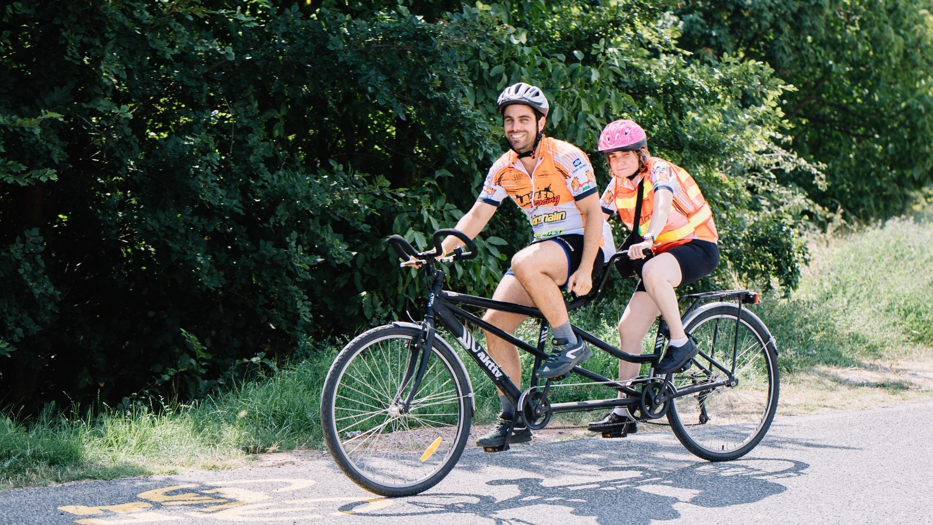 Two cyclists on a tandem bicycle outdoors.