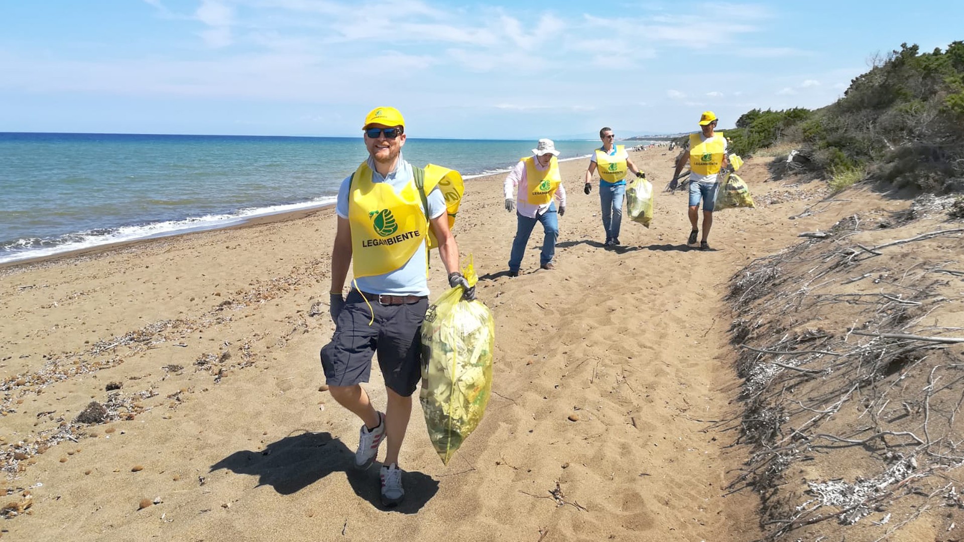 Beach cleanup volunteers carrying trash bags.