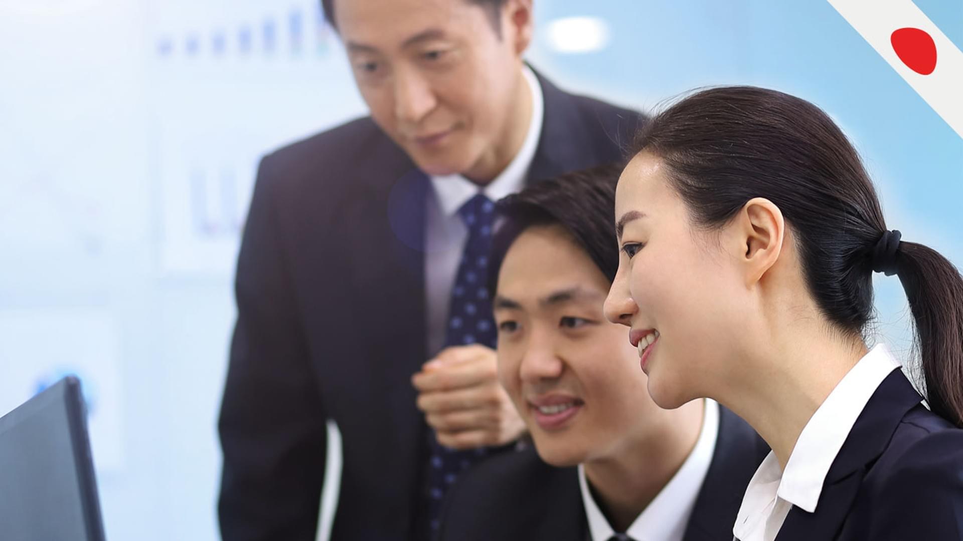 Business professionals collaborating over laptop in office.