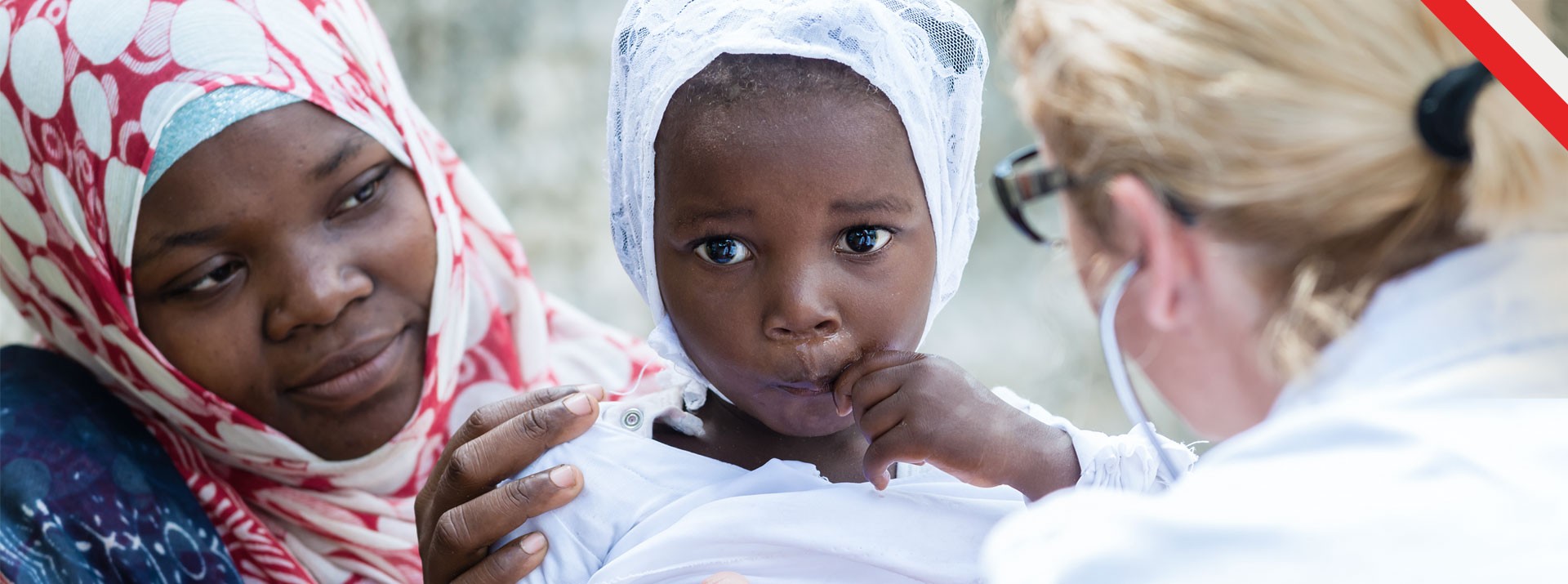 Mother and child receiving medical attention outdoors.