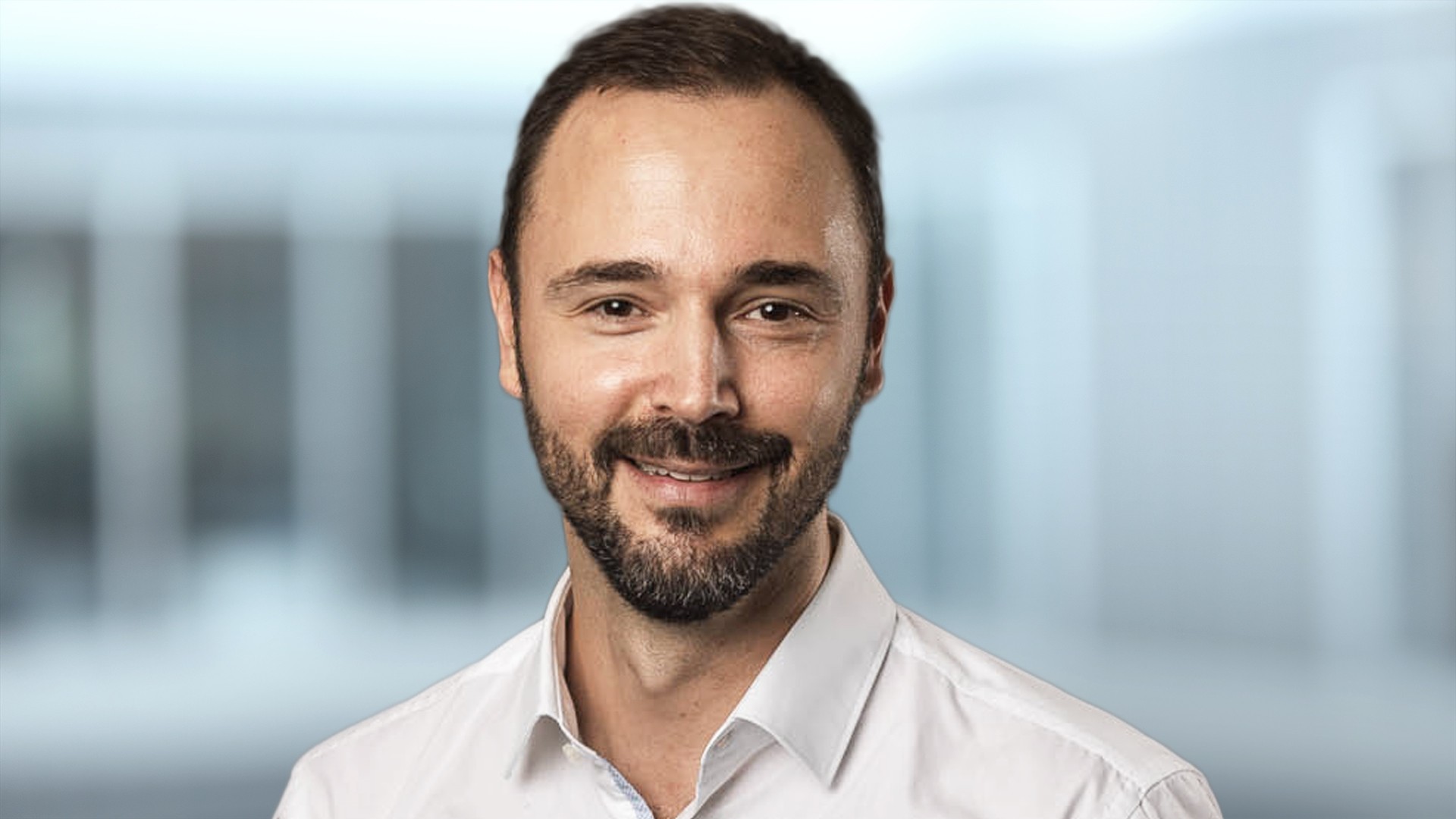 Smiling man wearing a white shirt, blurred