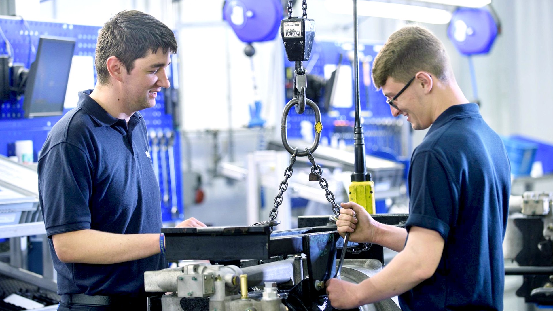 Two employees using equipment in a workshop.