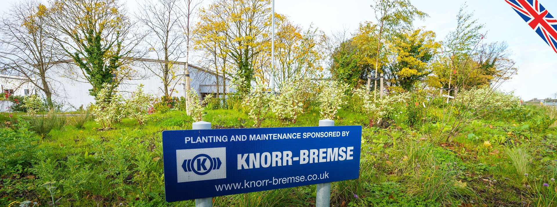 Knorr-Bremse-sponsored planting and maintenance sign in greenery.
