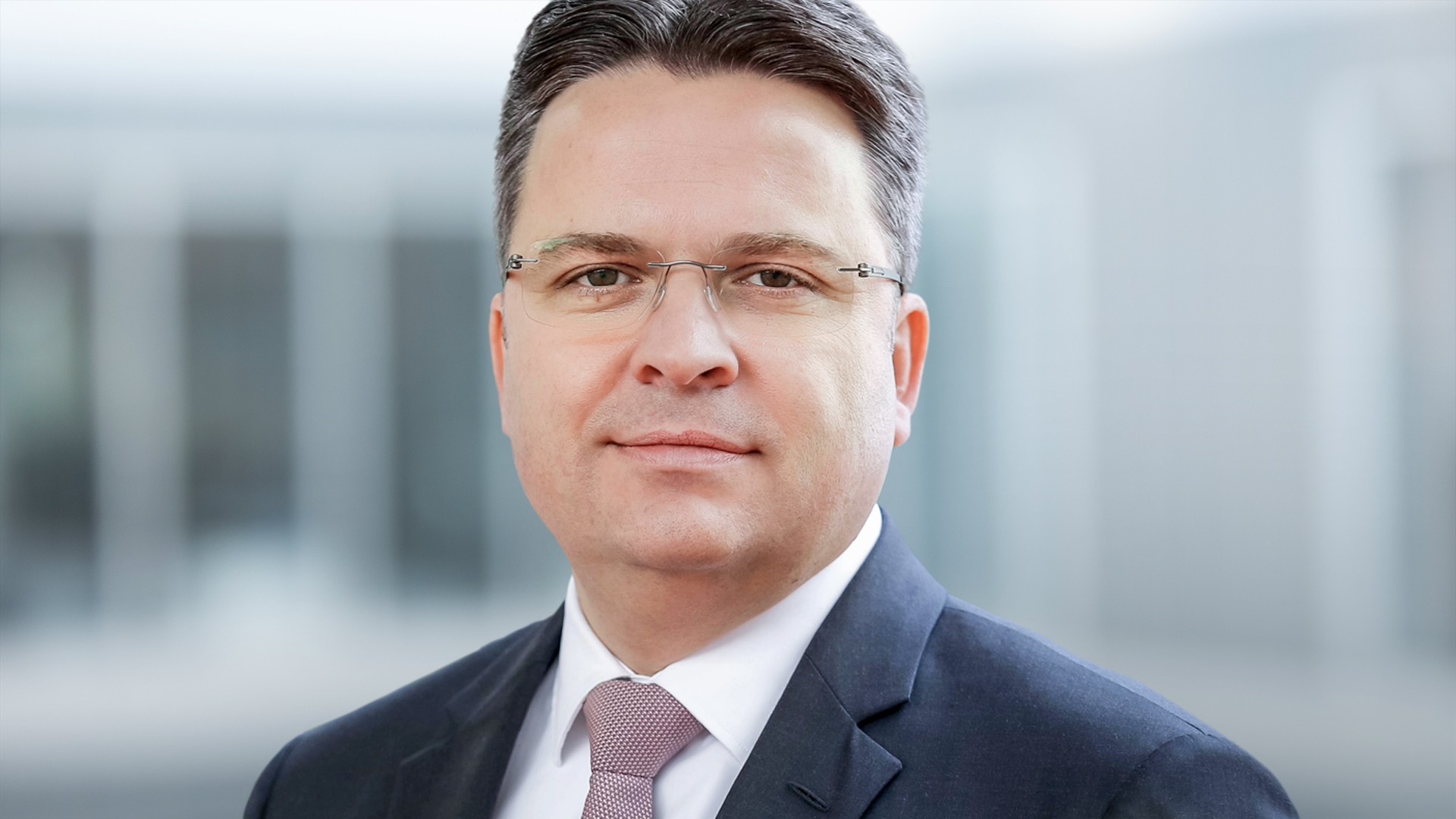 Professional man in suit with glasses outdoors.