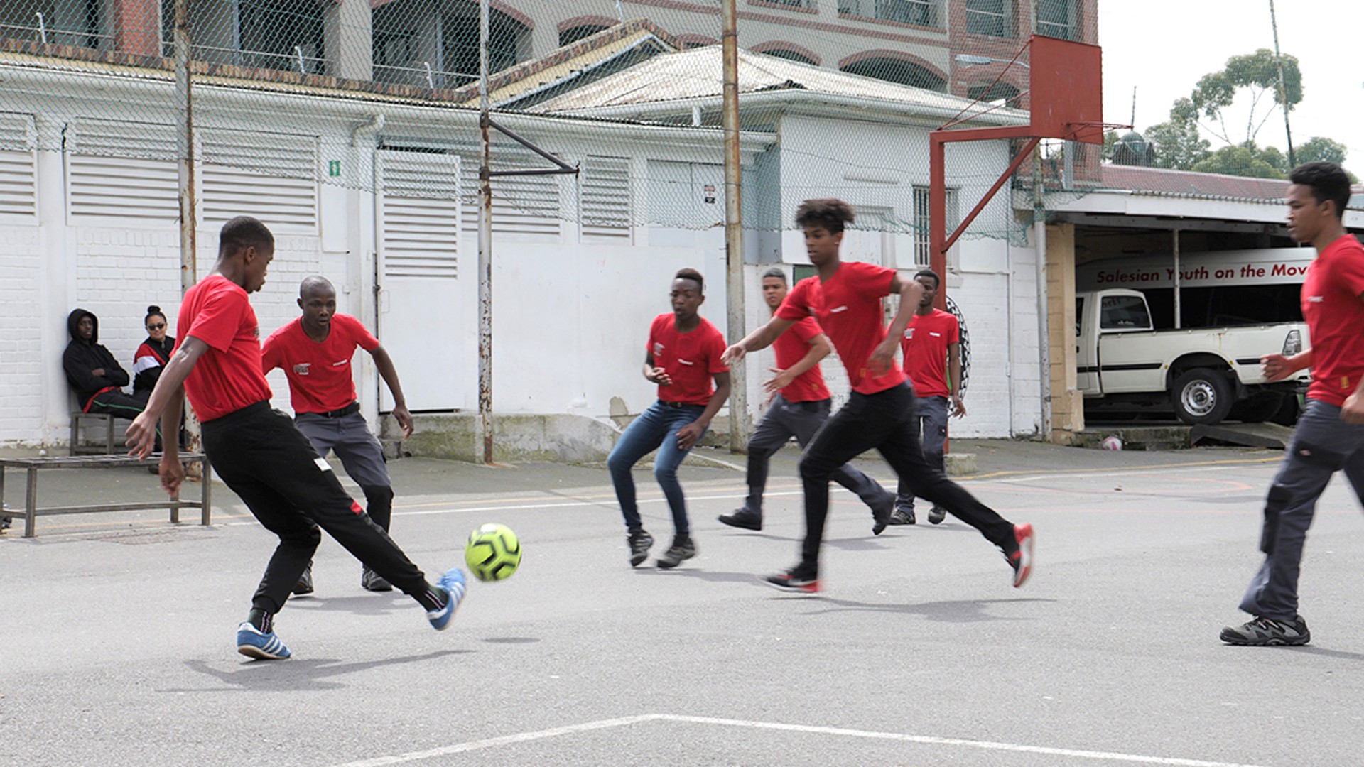 Young people playing soccer on urban court.