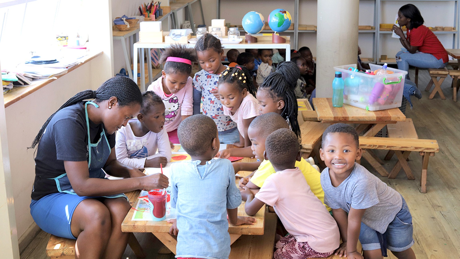 Children engaged in art activity with teacher.